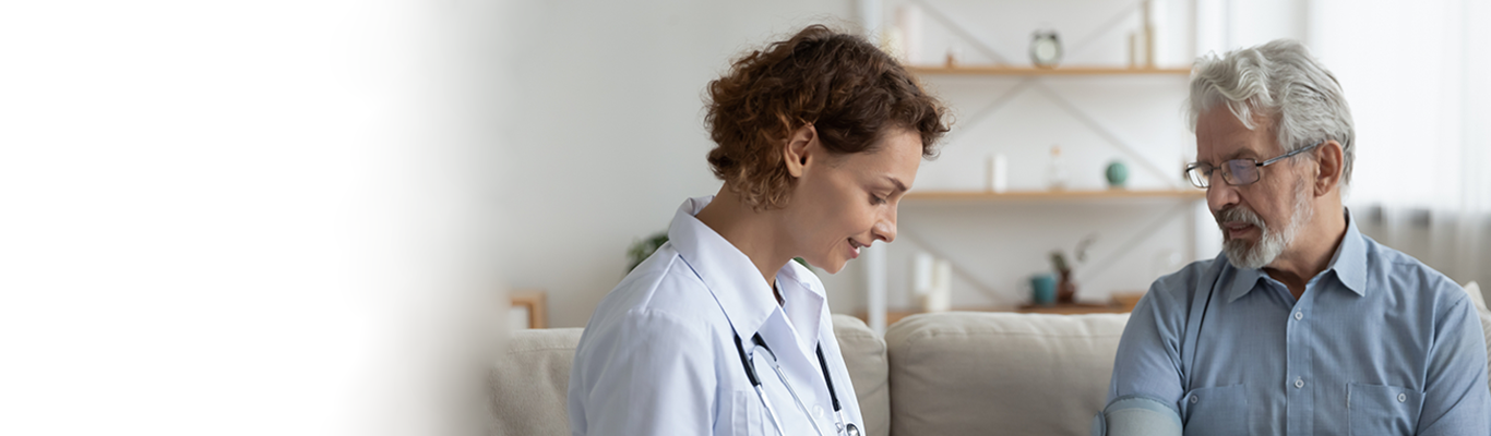 Ärztin misst Blutdruck beim Patienten